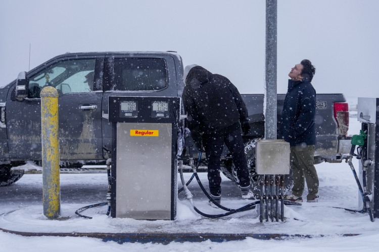 Edwin Solomon, 18, right, stands in the wind and snow while filling up a truck with regular gas at a price of $7.50 a gallon in Kaktovik, Alaska. AP