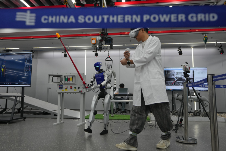 A staff member demonstrates the remote controls of a robot working on a mock power grid control unit during a media organized tour at Guangdong Power Grid Robotics Laboratory in Guangzhou, China. AP